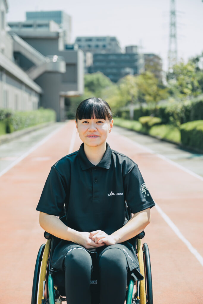 陸上競技場でほほえむ西村さんの写真